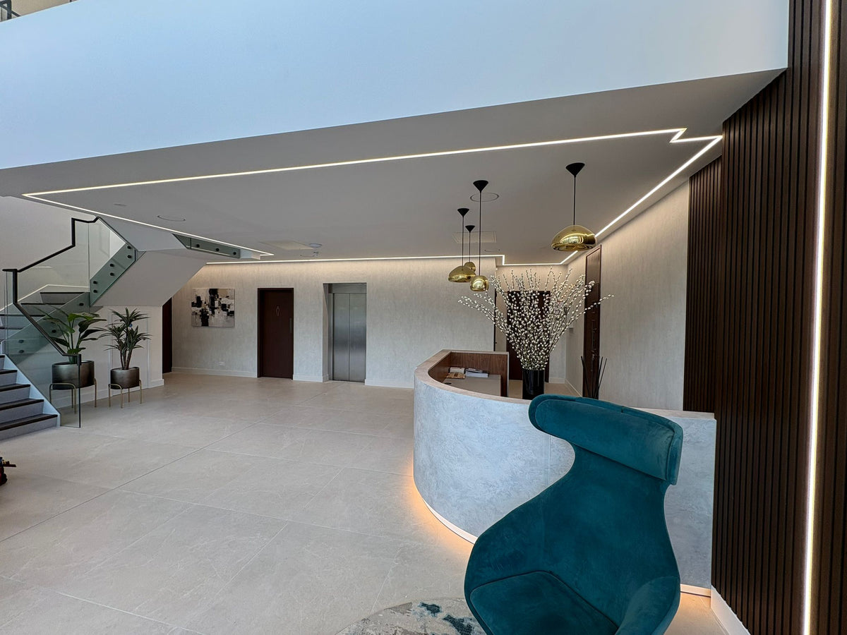 Completed reception interior with a curved counter, illuminated plinth and timber slat wall
