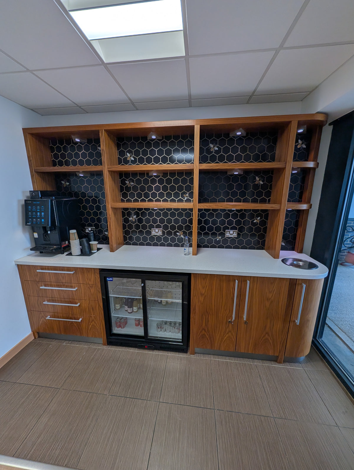 Fitted timber-effect coffee station with shelving and a white counter